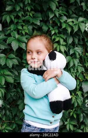 Ragazza impressionabile che abbraccia il suo panda giocattolo. Bambina innamorata del suo giocattolo. Foto Stock