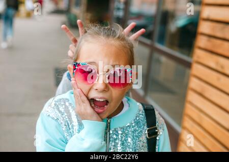 Poco elegante kids in occhiali da sole per divertirsi in una strada di città Foto Stock