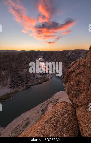 Una splendida vista verticale del paesaggio delle cascate di Augrabies Gorge, montagne e fiume in Sud Africa, presa subito dopo il tramonto con cl rosa e giallo Foto Stock