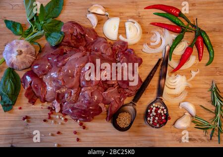 Fegato di pollo crudo e varie spezie sul tagliante Foto Stock