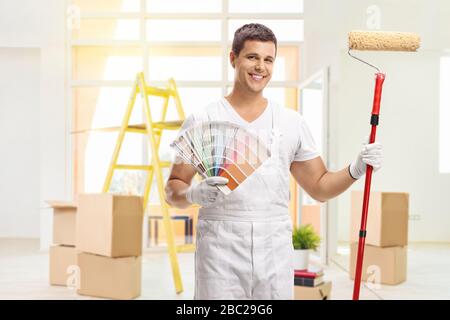 Pittore di casa con un orologio a colori e un rullo di vernice all'interno di una casa Foto Stock