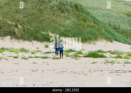 Ein Mann und eine Frau laufen in den Dünen entlang Foto Stock