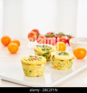 Muffin, paleo, keto dieta. Frittata con spinaci, verdure, pomodori cotti in piccoli stampi Foto Stock