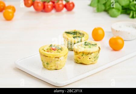 Muffin, paleo, keto dieta. Frittata con spinaci, verdure, pomodori cotti in piccoli stampi Foto Stock