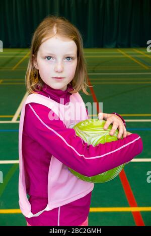 La bambina di 10 anni tiene in mano / tiene in mano una palla a rete sul campo alla fine di una lezione / gioco interna / interna di nettball. (116) Foto Stock