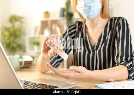 Primo piano di donne imprenditrici mani utilizzando igienizzatore strofinare evitando contagio siting su una scrivania in casa ufficio Foto Stock