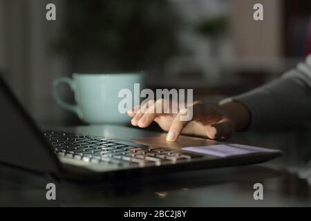 Primo piano della mano della ragazza usando il portatile su una scrivania a casa di notte Foto Stock