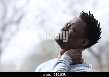 Uomo nero che soffre mal di collo lamentarsi all'aperto Foto Stock