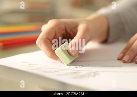 Primo piano delle mani della donna utilizzando la gomma che cancella il disegno della matita su una scrivania a casa Foto Stock