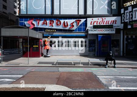 lone seduto con maschera di protezione sul telefono cellulare , vuoto Times Square durante la pandemia di cornavirus 1 aprile 2020 Foto Stock