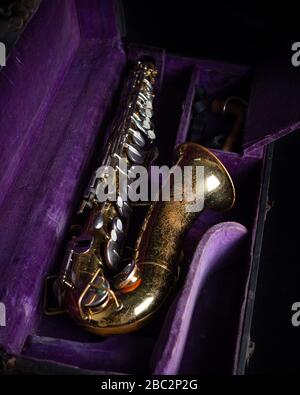 Buescher Alto Sax, laccato oro in custodia rigida con rivestimento in velluto viola scuro in caso di fondo nero Foto Stock