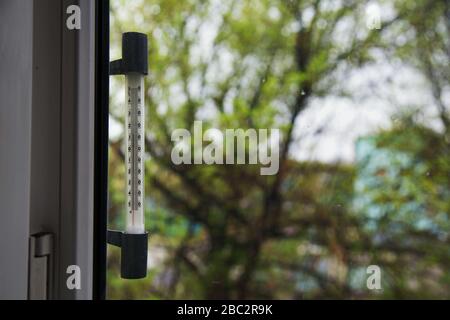 Termometro a finestra con liquido in vetro che mostra la temperatura esterna. Calibrato in gradi Celsius e fissato all'esterno della finestra, backgrou sfocato Foto Stock