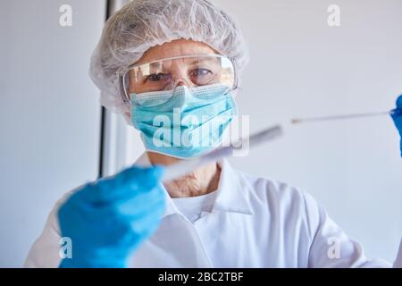 Test di striscio della saliva per il test rapido di Covid-19 con professionisti medici in laboratorio durante un'epidemia di coronavirus Foto Stock