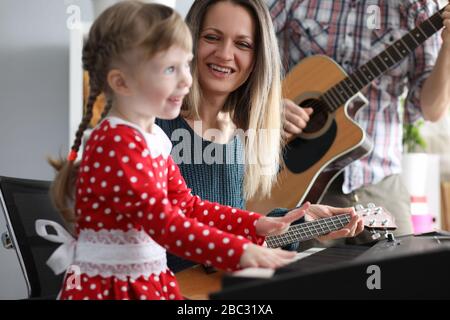 I genitori suonano chitarre, figlia sul sintetizzatore Foto Stock