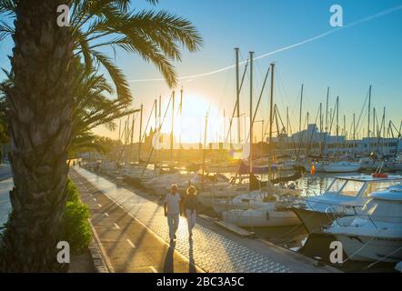 Coppia a piedi al Sunrise Paseo Maritimo con porto e Cattedrale, Palma di Maiorca, Baleari, Spagna Foto Stock