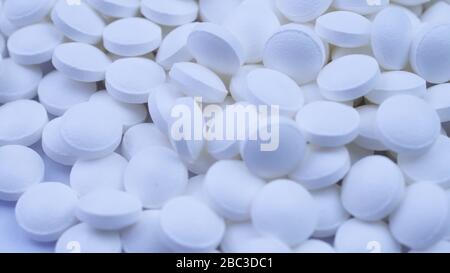 Un gran numero di vitamine bianche si trovano nelle vicinanze e ruotano sul tavolo da vicino Foto Stock