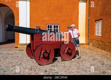 Kronborg, Danimarca -- 26 luglio 2019. Foto grandangolare di un turista che esamina un cannone al famoso castello di Kronborg in Danimarca. Foto Stock