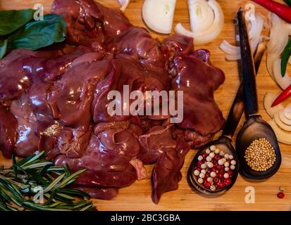 Fegato di pollo crudo e varie spezie sul tagliante Foto Stock