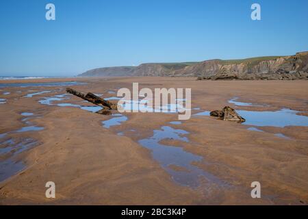 Pericolosi pezzi di relitto che si attaccano dalla spiaggia saranno nascosti quando la marea è dentro. Bella spiaggia di Sandymouth, Bude Bay, Cornwall Foto Stock