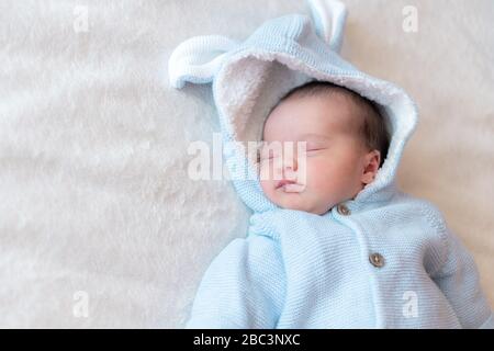 Primo piano sul neonato, posizionare il testo. Neonato che dorme sulla schiena in una blusa blu su una vista dall'alto di sfondo bianco. Ritratto di un neonato addormentato Foto Stock