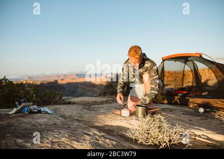 camper in camo costruisce un forno sussurro in ritardo preparandosi per la cena Foto Stock