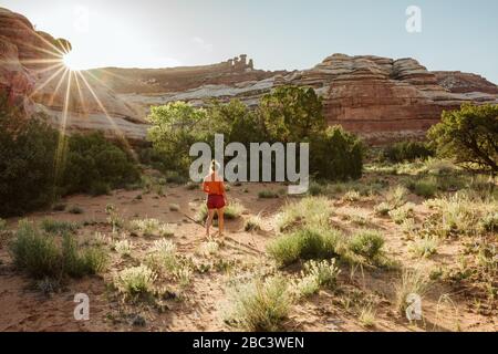 donna si allontana mentre il sole tramonta sulle pareti del canyon in un'oasi del deserto Foto Stock