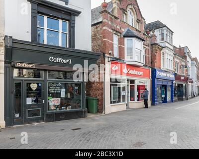 Una persona che utilizza un bancomat bancario per ottenere denaro in una strada vuota a Abergavenny durante il focolaio di coronavirus, Galles, Regno Unito Foto Stock