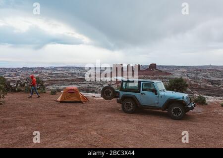 jeep parcheggiata accanto a una tenda arancione in una giornata piovosa a canyonlands utah Foto Stock