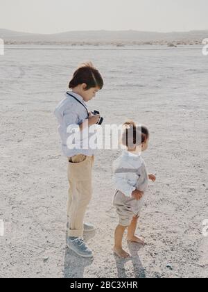 Ritratto di un bambino che tiene una macchina fotografica mentre un altro bambino si alza accanto lui Foto Stock