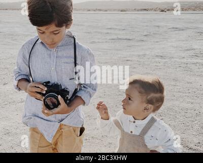 Un bambino tiene una macchina fotografica ed un bambino più giovane sta vicino a me Foto Stock