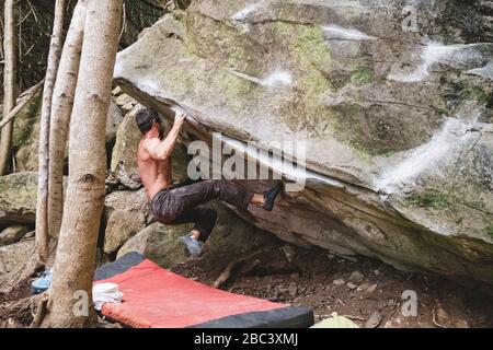 Un arrampicatore di roccia maschile sale una roccia all'aperto Foto Stock