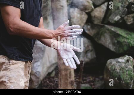 Primo piano delle mani dell'arrampicatore che si aggrafano con il gesso Foto Stock