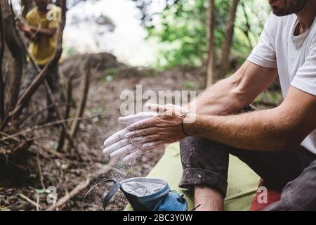 Primo piano delle mani dell'arrampicatore di roccia che si aggrafano le mani con il gesso Foto Stock