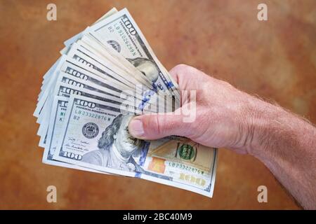 mans hand holding fanned out hundred dollar US bills Foto Stock
