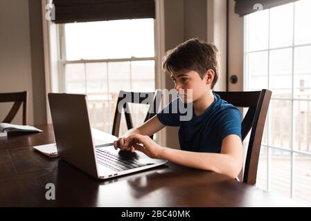 Tween ragazzo che lavora a casa con un notebook per pendolari. Foto Stock