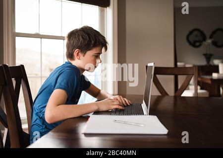 Tween ragazzo che lavora a casa con un notebook per pendolari. Foto Stock