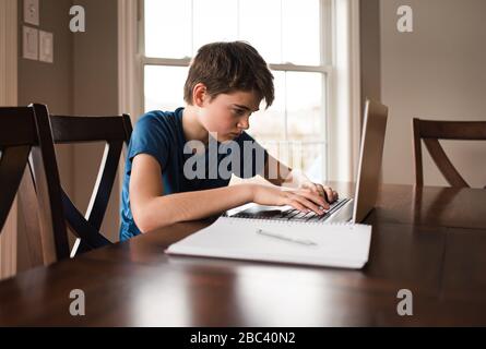 Tween ragazzo che lavora a casa con un notebook per pendolari. Foto Stock