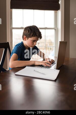 Tween ragazzo che lavora a casa con un notebook per pendolari. Foto Stock