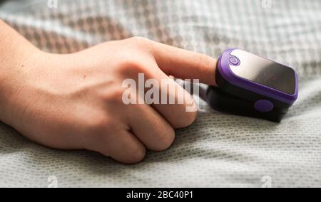 Primo piano di una mano con un pulsossimetro posizionato sul dito. Foto Stock