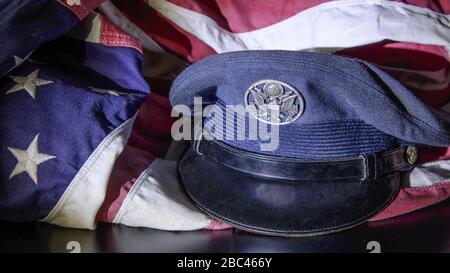 Primo piano, ancora vita di cappello militare vestito con bandiera americana drappeggiato intorno ad esso. Foto Stock