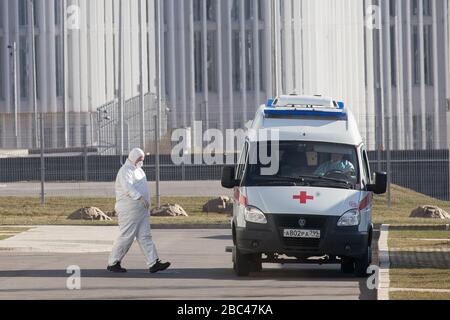 Mosca, Russia. 25th Mar, 2020. Un medico specialista che indossa gli attrezzi protettivi cammina vicino ad un'ambulanza fuori di un ospedale a Kommunarka, distretto amministrativo di Novomoskovskiy, regione della Nuova Mosca durante la pandemia del nuovo coronavirus (COVID-19). L'ospedale offre il trattamento a pazienti confermati e potenziali con infezione da COVID-19 e infezione virale respiratoria acuta. Foto Stock