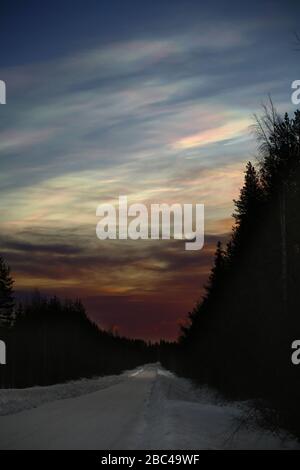 Nacreous nuvole al mattino su strada invernale. Foto Stock