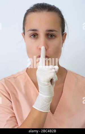 Donna del medico che chiede il silenzio con i guanti del lattice Foto Stock