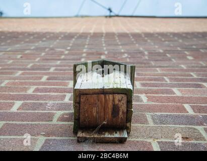 Vista ad angolo basso os una piccola casa di uccello di legno, apparentemente inutilizzato e stagionato, attaccato ad una grande parete esterna di mattoni di una tipica casa indipendente in Th Foto Stock