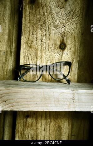 Un paio di occhiali neri su una sporgenza di legno di una capanna di legno. Foto Stock