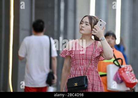 Una giovane ragazza cinese che usa il suo cellulare in Jianghan Road, Wuhan, Cina Foto Stock