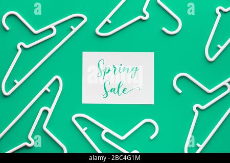 Appendiabiti in plastica bianca, testo "vendita a prezzo speciale" su carta. Creative vista dall'alto piatto adagiarsi su trendy sfondo verde menta pastello, composizione geometrica, creativo Foto Stock