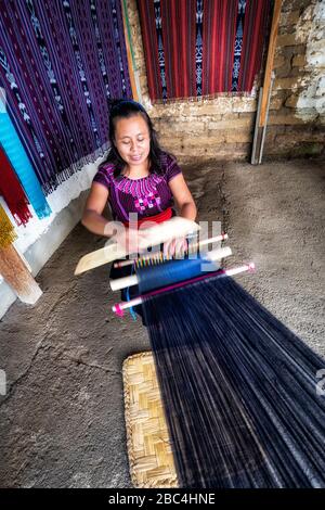 Una giovane donna si intreccia in una cooperativa nel villaggio di San Juan sulla riva del lago Atitlan, Guatemala. Foto Stock