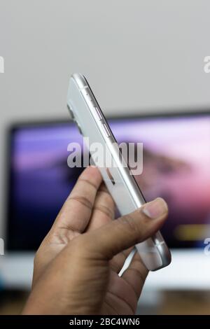 Sul retro dell'iPhone 11, variante bianca, tenendolo a portata di mano Foto Stock