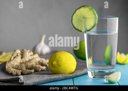 Una tazza d'acqua con limone, aglio e zenzero su un tavolo di legno blu. Prevenzione dei raffreddori. Maggiore immunità. Con spazio di copia Foto Stock